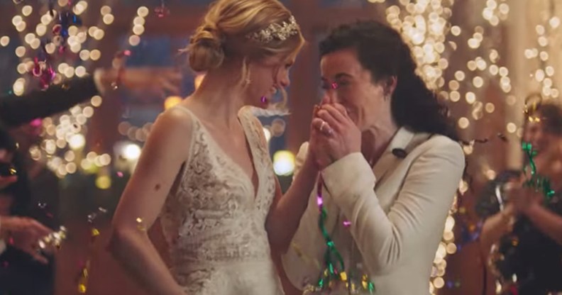 Two brides walking down the aisle, one is kissing the other's hand