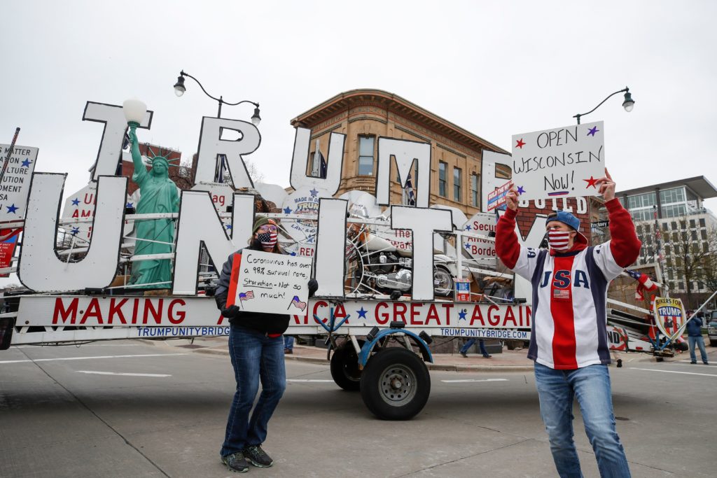 People hold signs during a protest against the coronavirus shutdown in front of State Capitol in Madison, Wisconsin, on April 24 2020. (KAMIL KRZACZYNSKI/AFP via Getty Images)