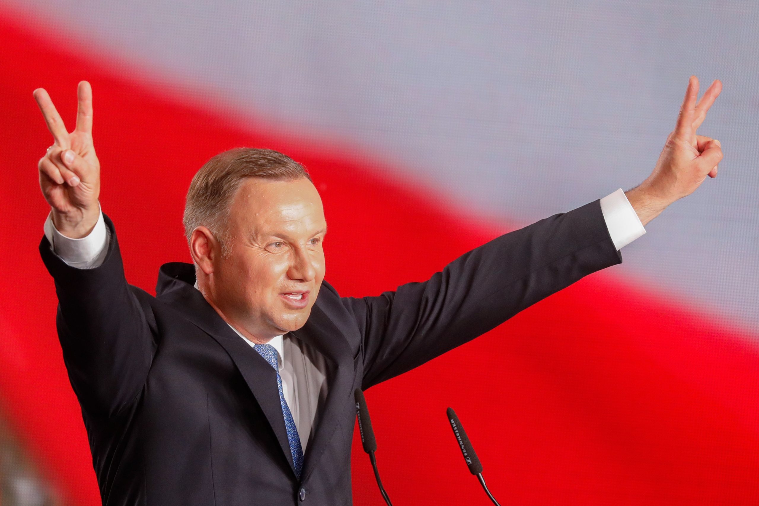 Polish President Andrzej Duda flashes V-signs after addressing supporters as exit poll results were announced during the presidential election in Lowicz, Poland 