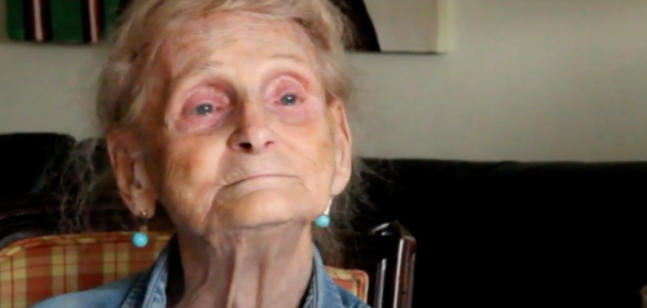 Robina Asti smiles in a denim shirt as she sits on a chair