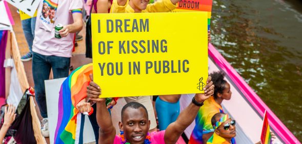 A black man holds a placard on the boat of Amnesty International during Amsterdam's famous canal pride parade