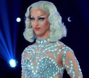 Miz Cracker in a blue wig and jewelled blue bodysuit