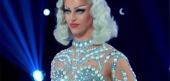 Miz Cracker in a blue wig and jewelled blue bodysuit