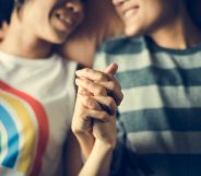 Lesbian couple holding hands, one wearing a rainbow t-shirt and another in a green striped top