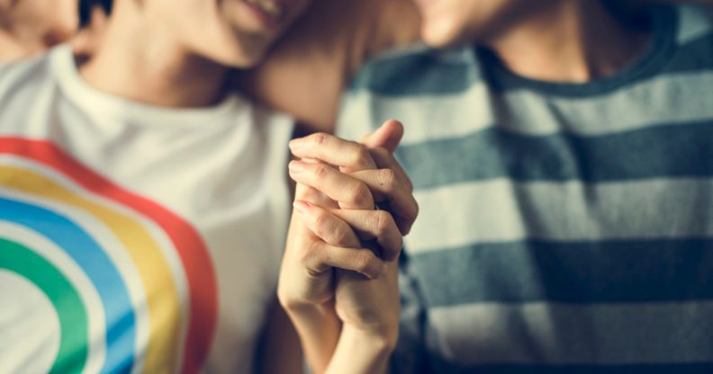 Lesbian couple holding hands, one wearing a rainbow t-shirt and another in a green striped top