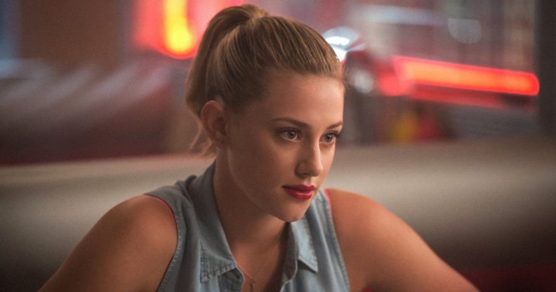 Lili Reinhart as Betty Cooper in Riverdale, wearing a sleeveless denim shirt, red lipstick and a ponytail