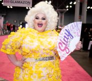 Darienne Lake in a yellow dress holding a hand fan