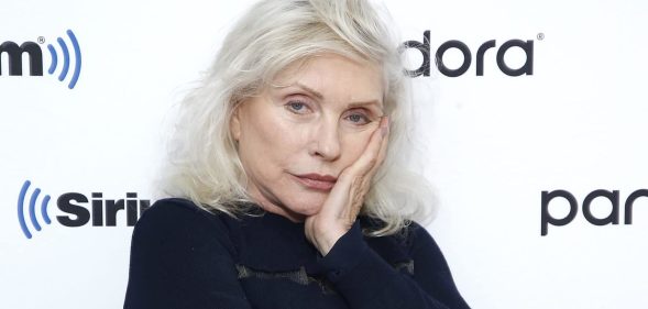 Debbie Harry in a black jumper with silver hair, resting her face on her hand