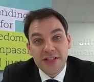 Alasdair Henderson speaking tot he camera with the EHRC signage behind him