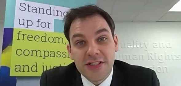 Alasdair Henderson speaking tot he camera with the EHRC signage behind him