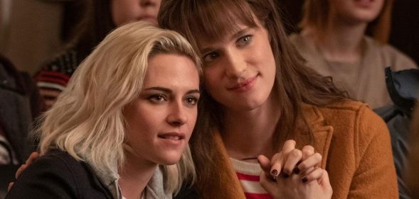 Kristen Stewart and Mackenzie Davis holding hands in Happiest Season