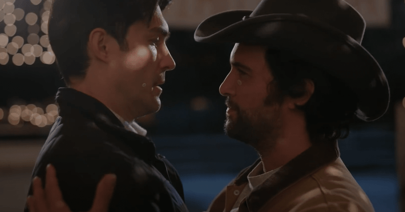 Two men embracing, one wearing a cowboy hat, in the Dashing in December trailer