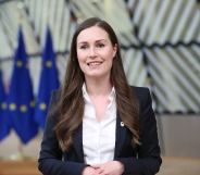 Sanna Marin is smiling in front of EU flags.