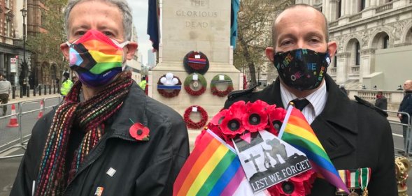 Peter Tatchell and David Bonney holding a rainbow poppy wreath at the Cenotaph