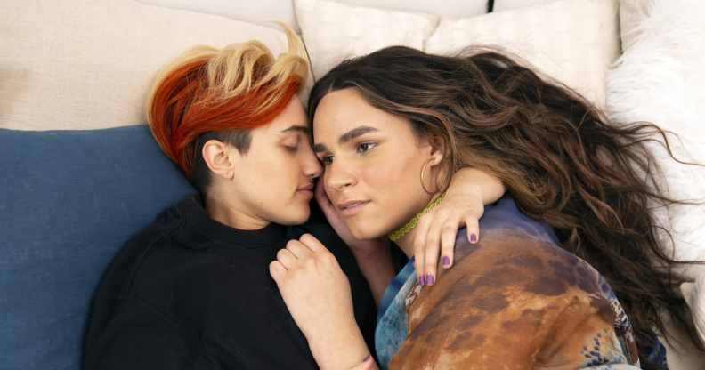 A transmasculine gender-nonconforming person and transfeminine non-binary person waking up together in bed