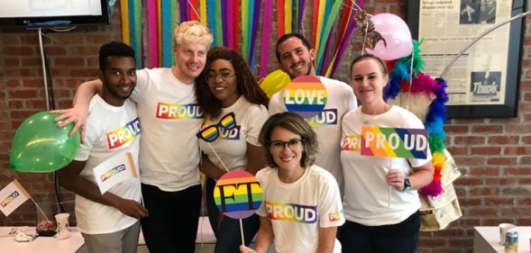 Members of Pride FT, the LGBT+ wing of the Financial Times, pose with rainbow 'proud' t-shirts and rainbow FT signs