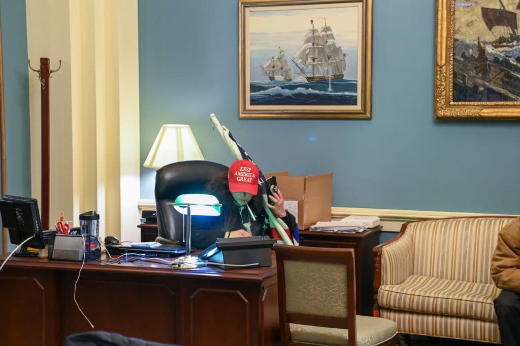 A supporter of US President Donald Trump sits inside the office of Speaker of the House Nancy Pelos