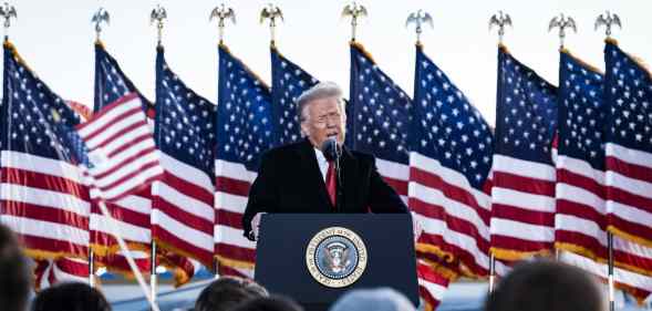 President Donald Trump speaks to his supporters on stage, American flags behind him