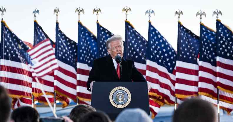 President Donald Trump speaks to his supporters on stage, American flags behind him