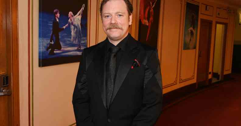 Rufus Hound smiles in a black blazer, shirt and tie