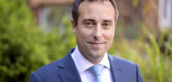 Nicholas Hewlett smiles in a blue suit