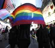 Americans holding a pride flag and trans flag in the background during a protest.