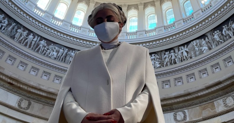 Lady Gaga in a white sheath cape and face mask, the rotunda of the Capitol complex framing her like a halo,