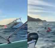 A boat sinks in the sea, surrounded by passengers floating in life vests