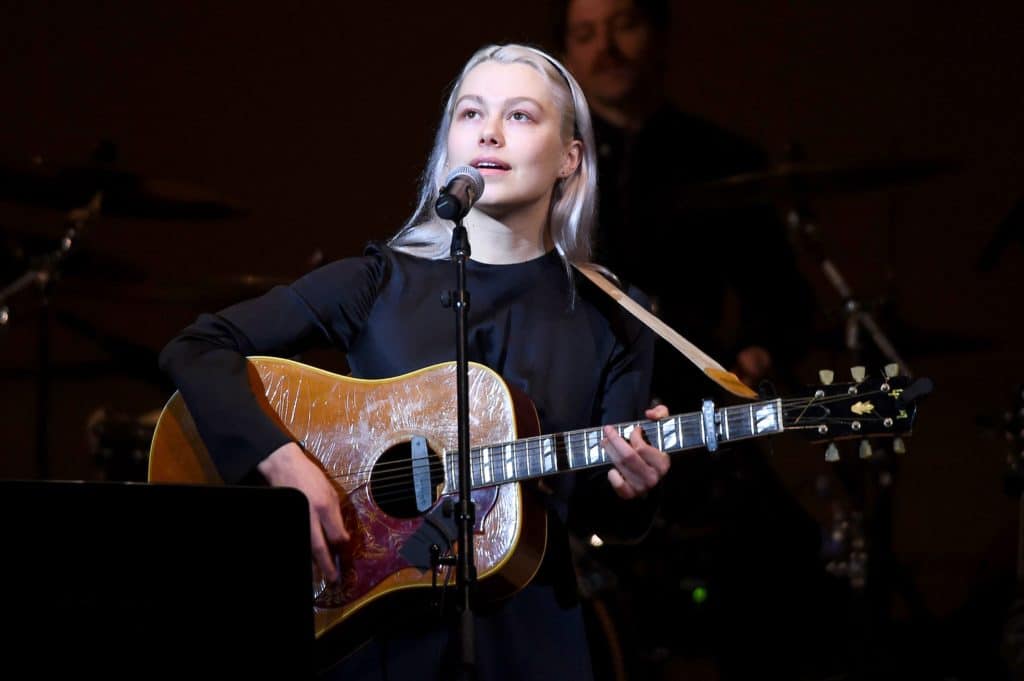 Phoebe Bridgers performs on stage holding a guitar