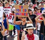 A woman with a QAnon shirt stands among an anti-vaccination protes