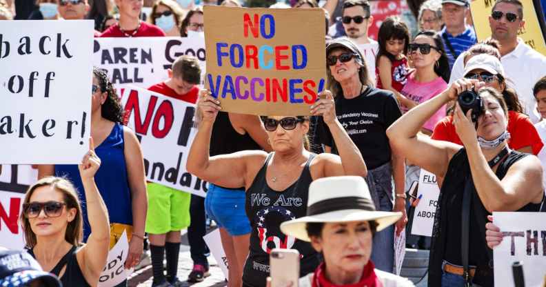 A woman with a QAnon shirt stands among an anti-vaccination protes