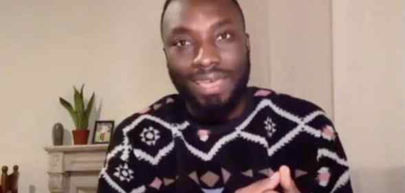 Ignatius Annor speaks in his home wearing a patterned jumper