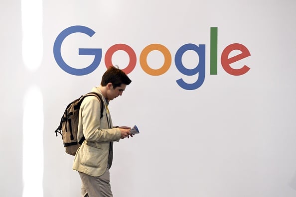 A man walks past the logo of Google