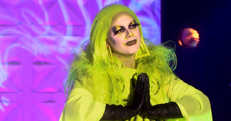 Ginny with her hands together in a prayer motion, wearing a highlighter yellow dress and matching hair