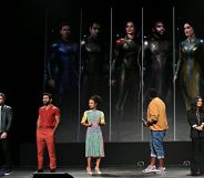 Richard Madden, Kumail Nanjiani, Lauren Ridloff, Brian Tyree Henry, and Salma Hayek on a stage infant of images of them in superhero costume