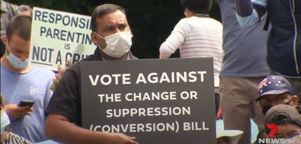 Man holding up sign that reads Vote against the change or suppression (conversion) bill