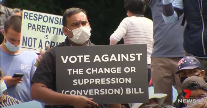 Man holding up sign that reads Vote against the change or suppression (conversion) bill