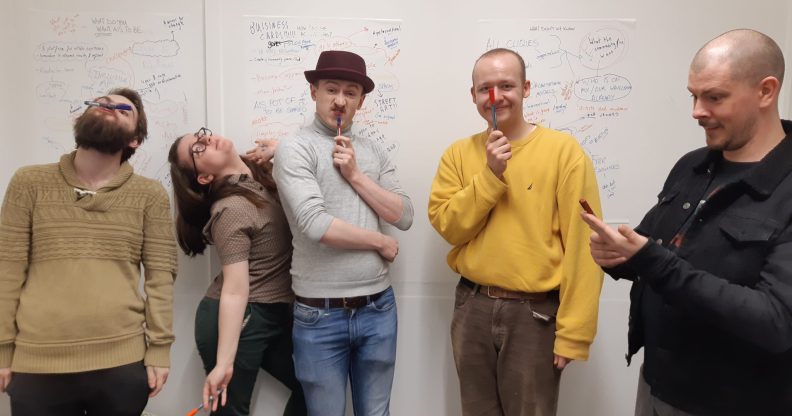 Five people standing in front of a whiteboard