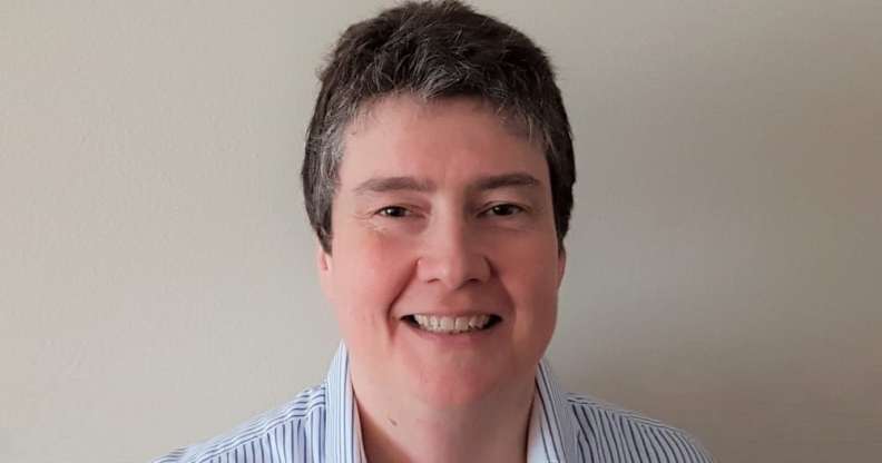 Census director Nicola Tyson-Payne smiling in a blue striped shirt, standing against a white wall