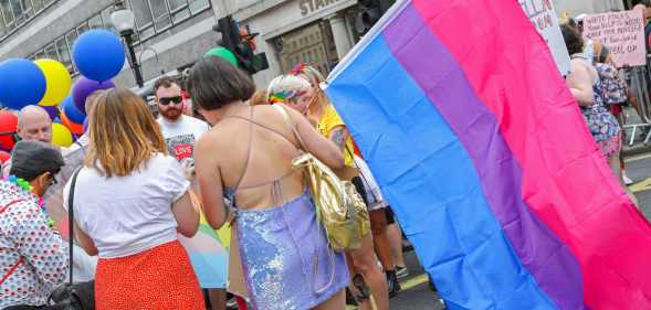 Parade goers with one holding the Bisexual Pride flag during Pride in London 2019