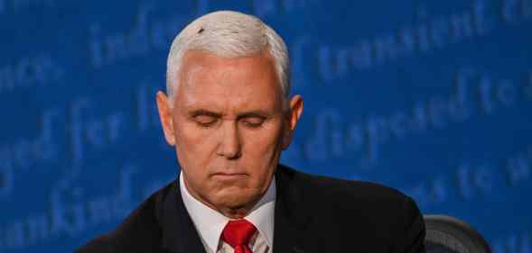 A fly rests on the head of Mike Pence as he takes notes during the vice presidential debate against Kamala Harris