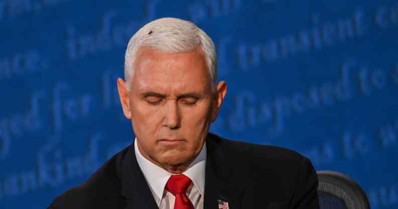 A fly rests on the head of Mike Pence as he takes notes during the vice presidential debate against Kamala Harris