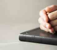 Hands closed in prayer on Holy Bible