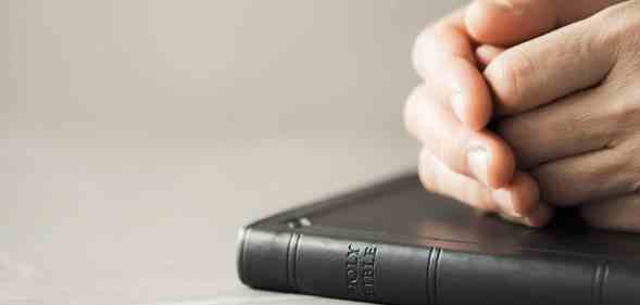 Hands closed in prayer on Holy Bible