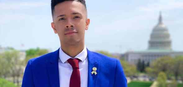 Pulse shooting survivor and gun reform activist Brandon Wolf dressed in a blue suit jacket, white shirt and red tie stands with Washington's Capitol building behind him in the distance