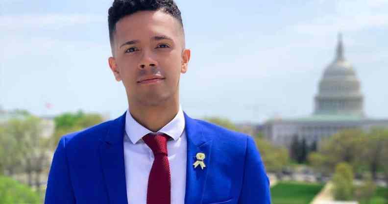 Pulse shooting survivor and gun reform activist Brandon Wolf dressed in a blue suit jacket, white shirt and red tie stands with Washington's Capitol building behind him in the distance