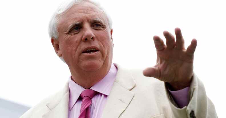 Jim Justice gestures with his hand in a white suit, pink shirt and pink tie outside