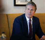 Keir Starmer watches on sat in a cushioned chair wearing a suit