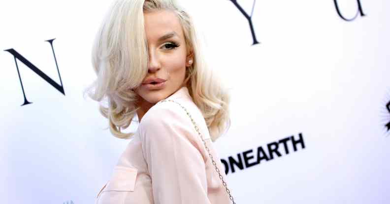 Courtney Stodden poses to the camera on the red carpet in a light pink shirt