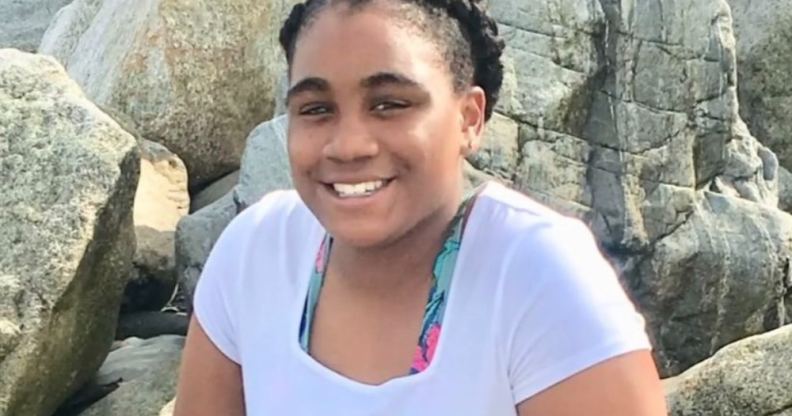 Mikayla Miller smiles in a white top, sat by some rocks